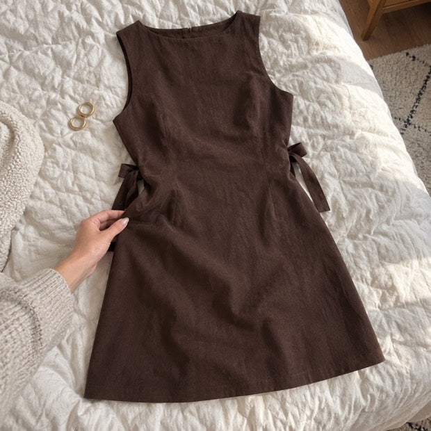 dress laid on a quilt with an adult hand showing the fabric.