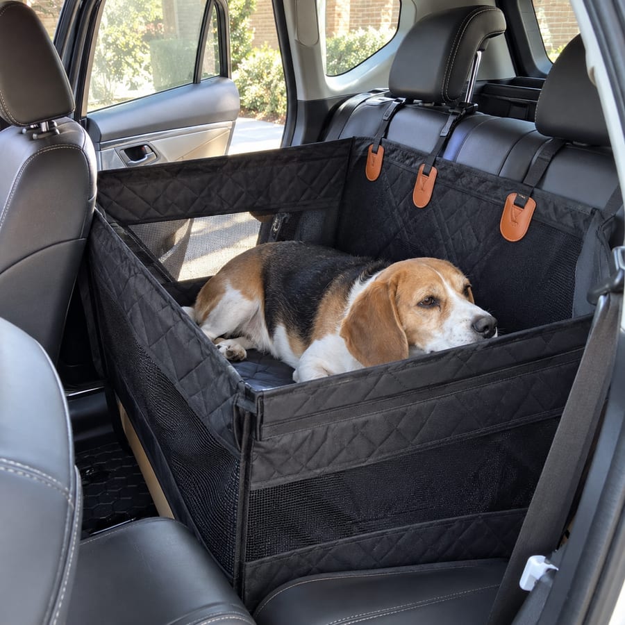 Beagle resting in the black pet travel seat in a parked car.