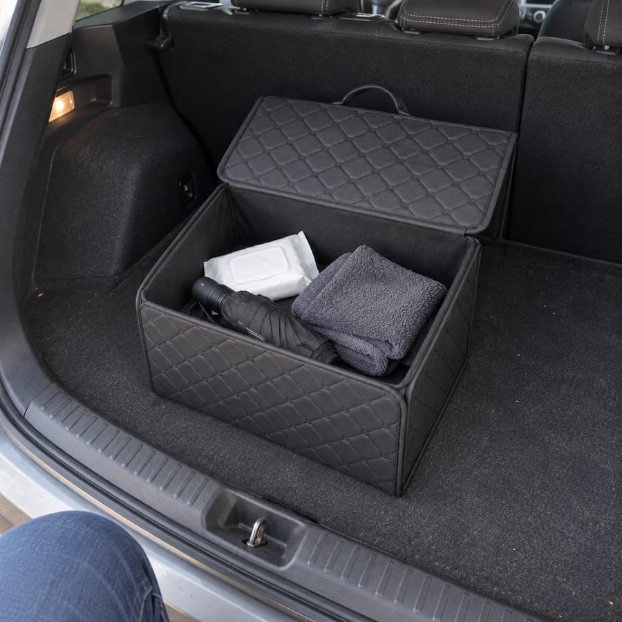 Open organizer with an umbrella and cloths in a compact car trunk.