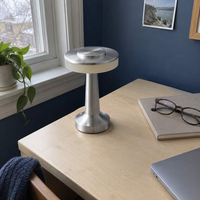 Silver C lamp switched off on a desk in natural daylight.