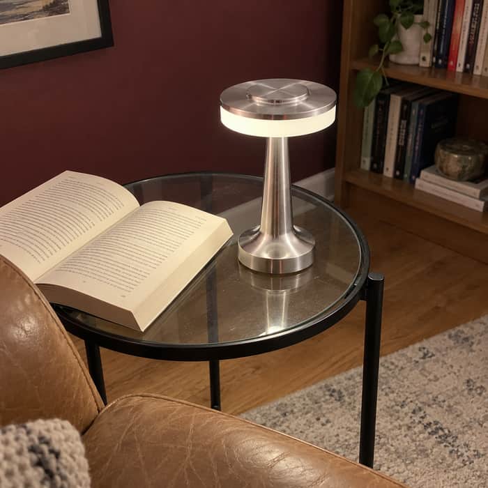 Silver C lamp beside a reading chair, photographed from above.