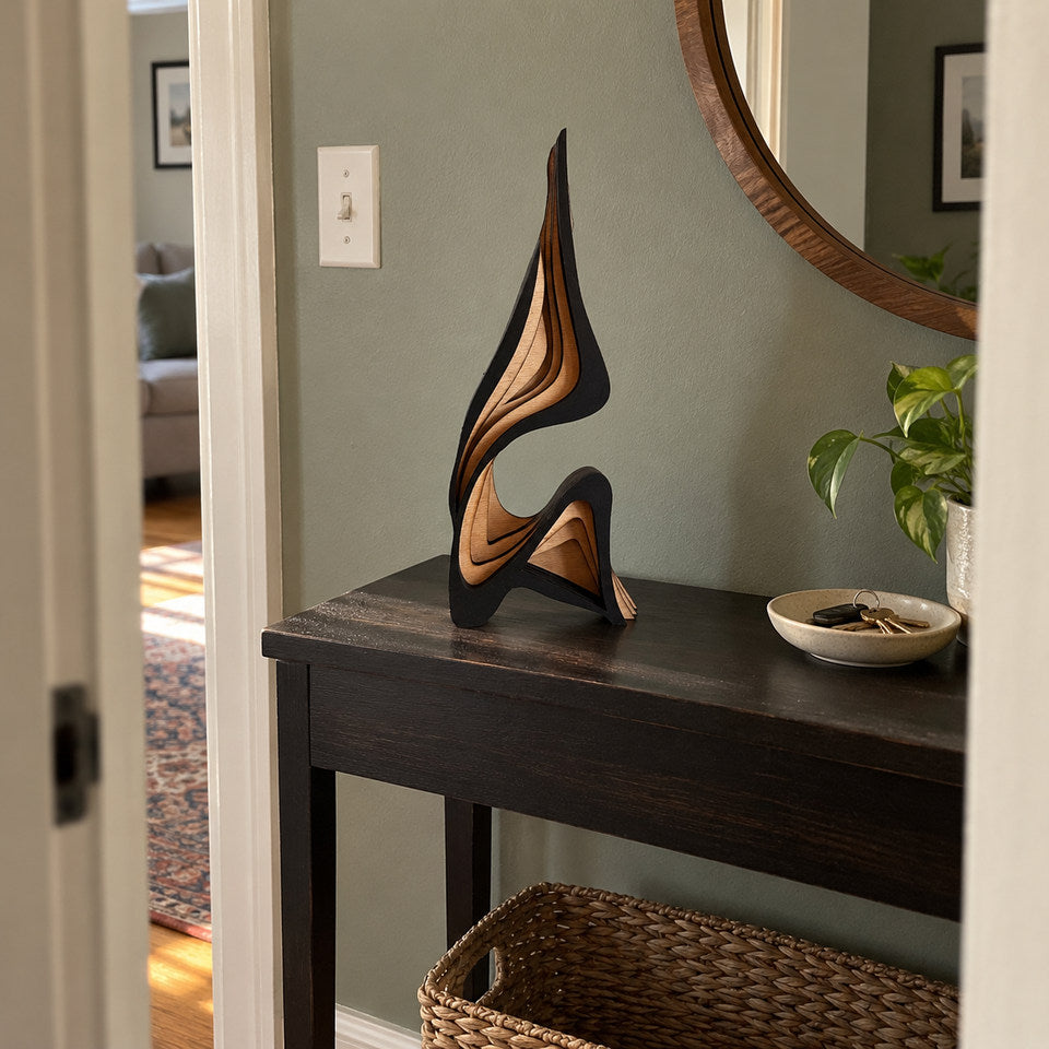 Tall sculpture on a simple dark console in a modest apartment entryway, photographed through a doorway from eye height.
