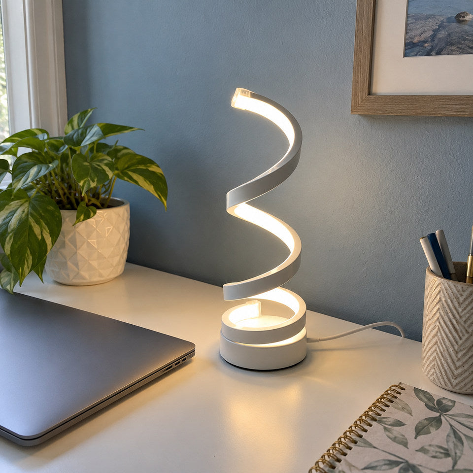 WHITE body spiral lamp from white reference on a small white desk, muted blue wall, closed laptop to one side.