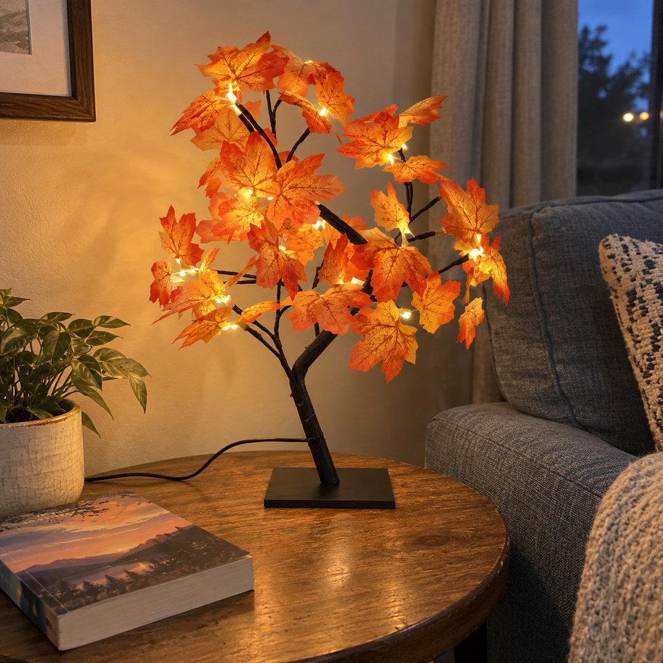 Only the Maple design from its own reference, orange leaves and black branches on its RECTANGULAR BLACK BASE, on a small side table beside a blue-grey sofa, a closed paperback nearby.