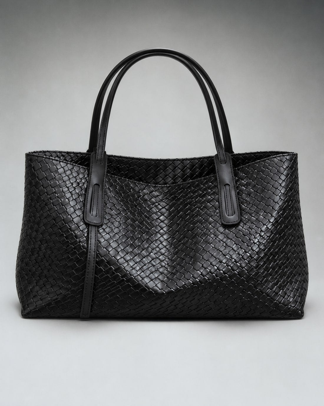 Black woven PU shoulder tote in a studio view