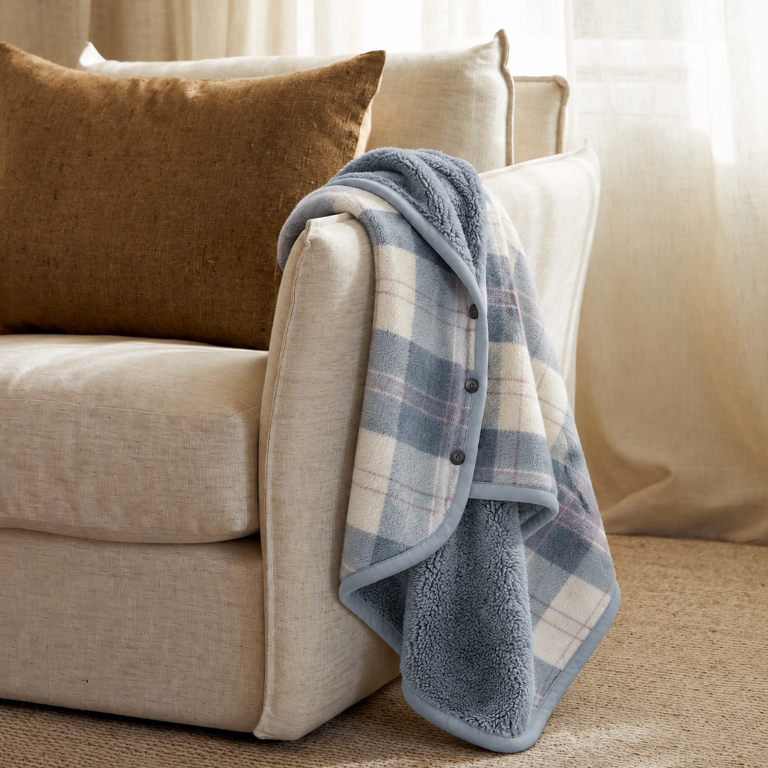 Blue Plaid blanket wrap with fleece lining draped on a sofa