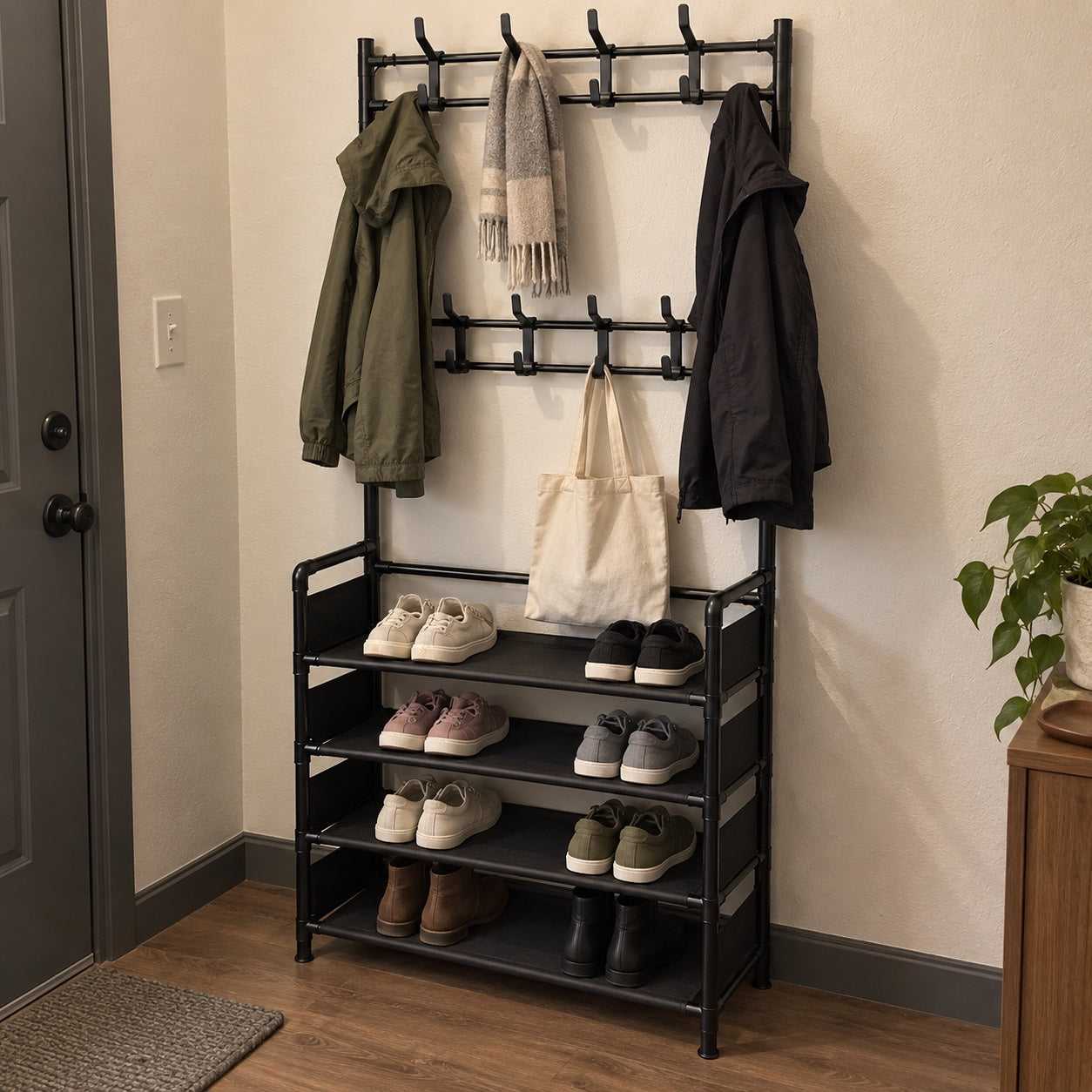 the black rack near a home entrance, with two jackets, a grey scarf, a beige canvas tote and everyday shoes and boots.