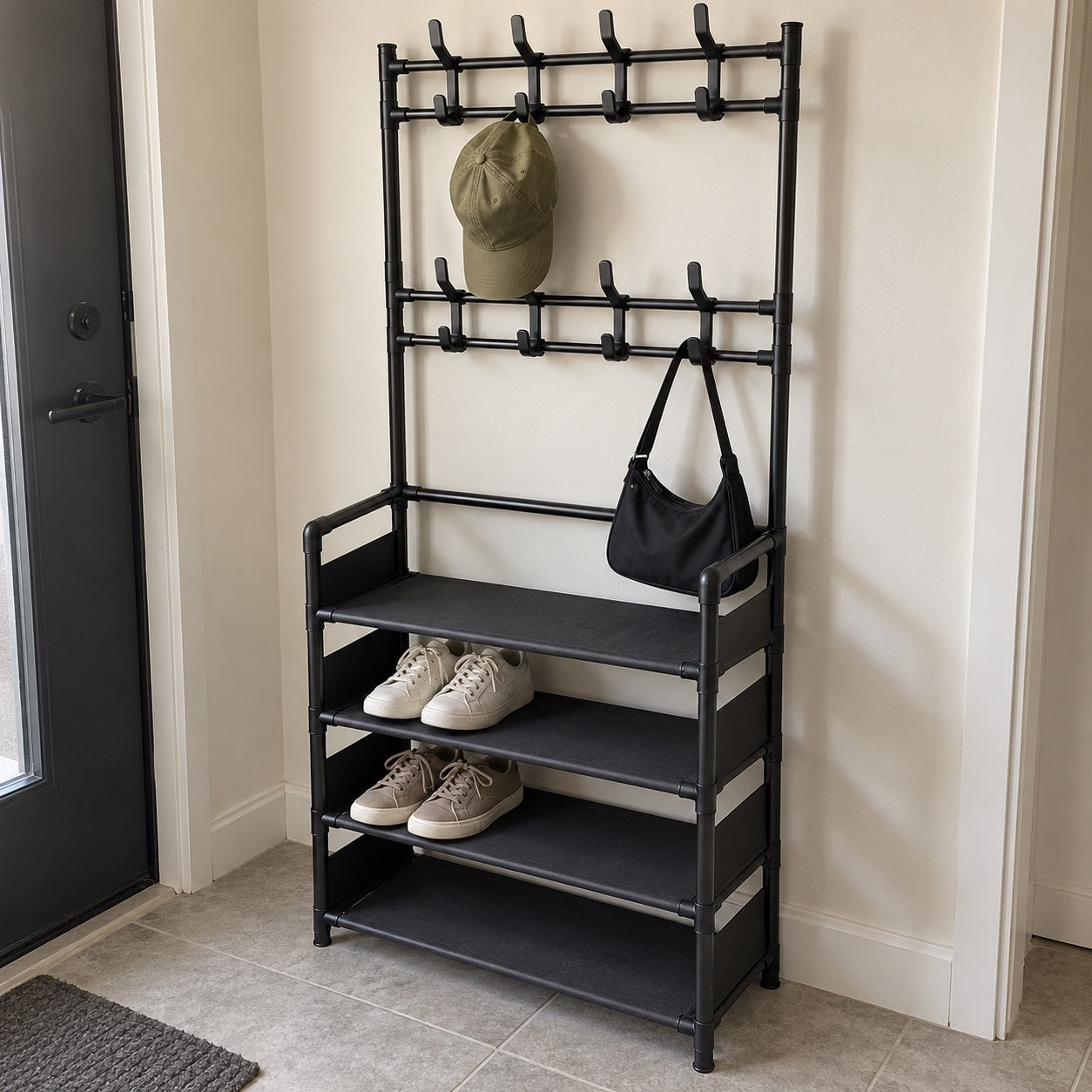the black rack in a tiled foyer, with an olive cap, black shoulder bag and two pairs of sneakers.