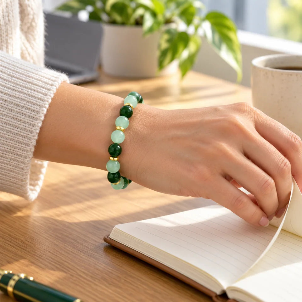 Single green bracelet on an adult wrist turning a blank notebook page at a desk.