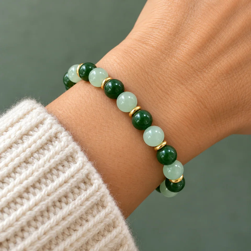 Close view of one green bracelet above a cream knit sleeve.