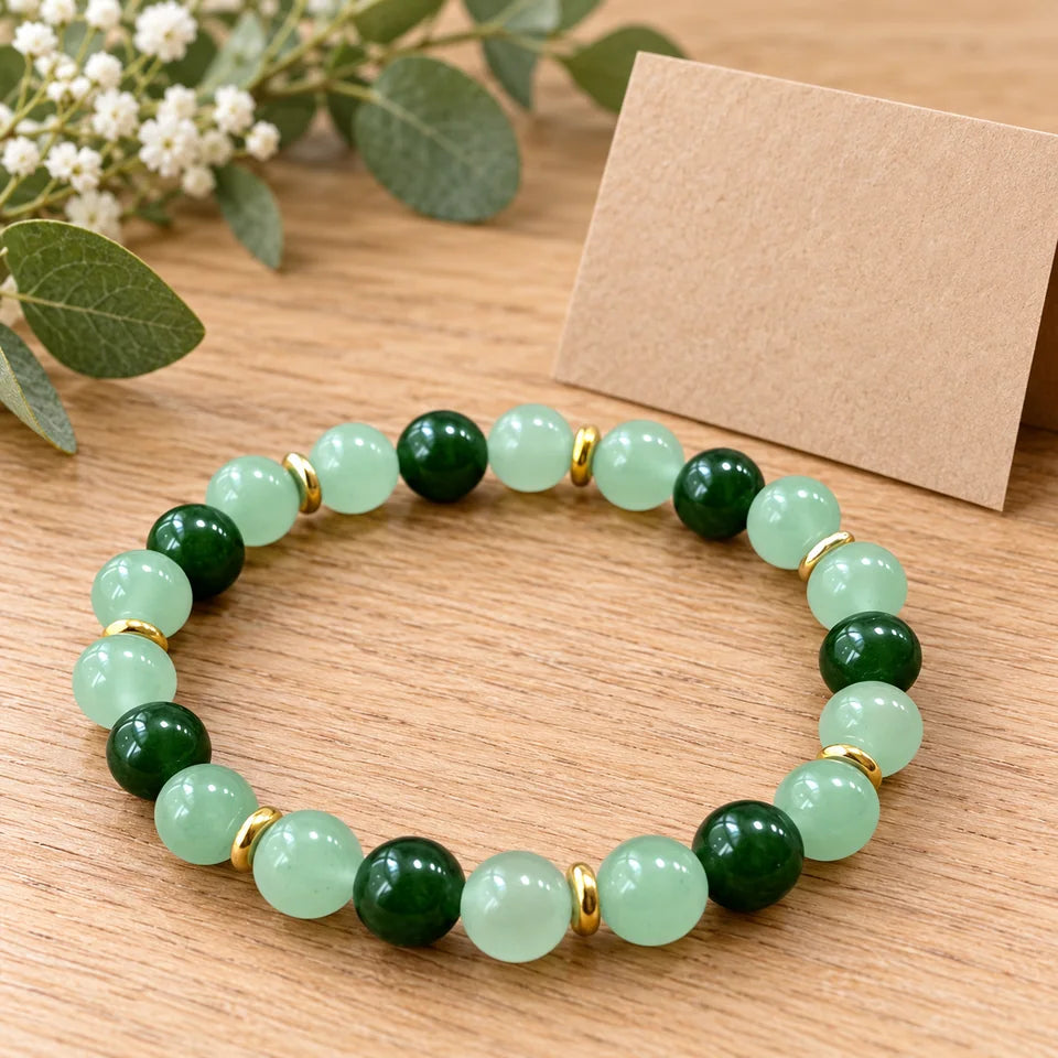 One green bracelet beside a separate blank kraft gift note on an oak table.