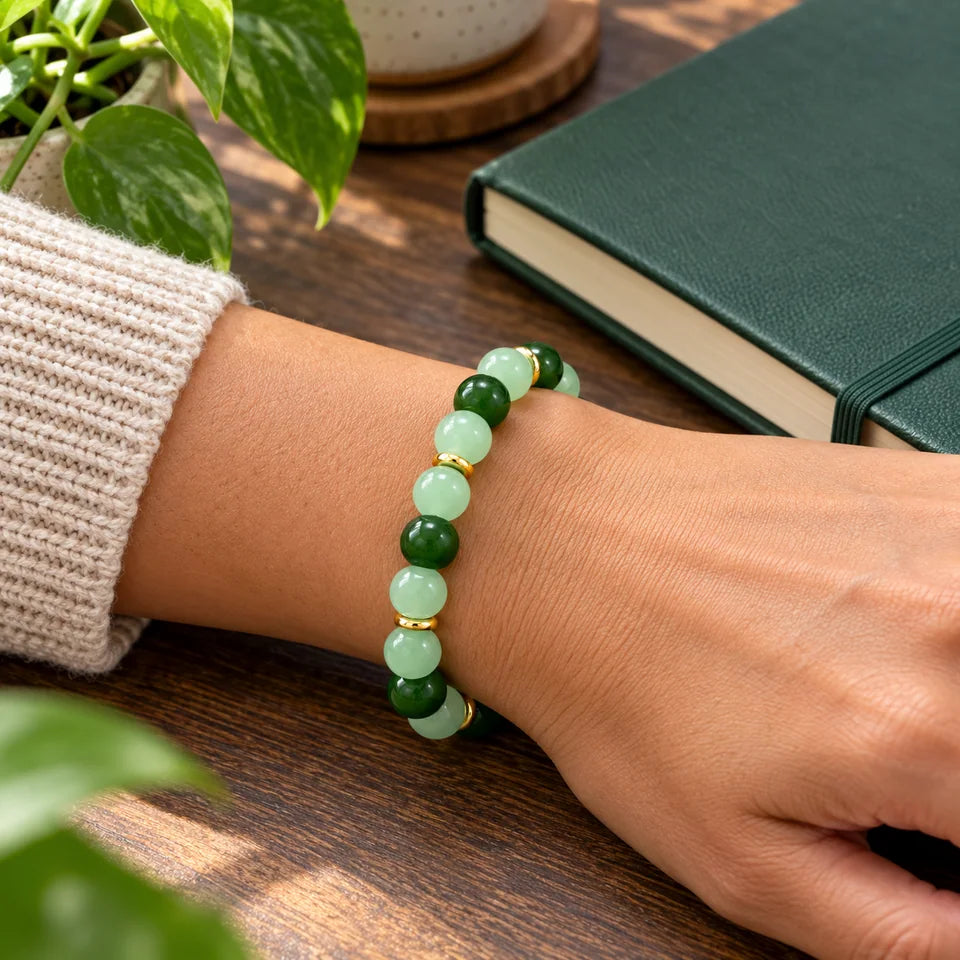 One green bracelet worn beside a closed forest-green notebook.