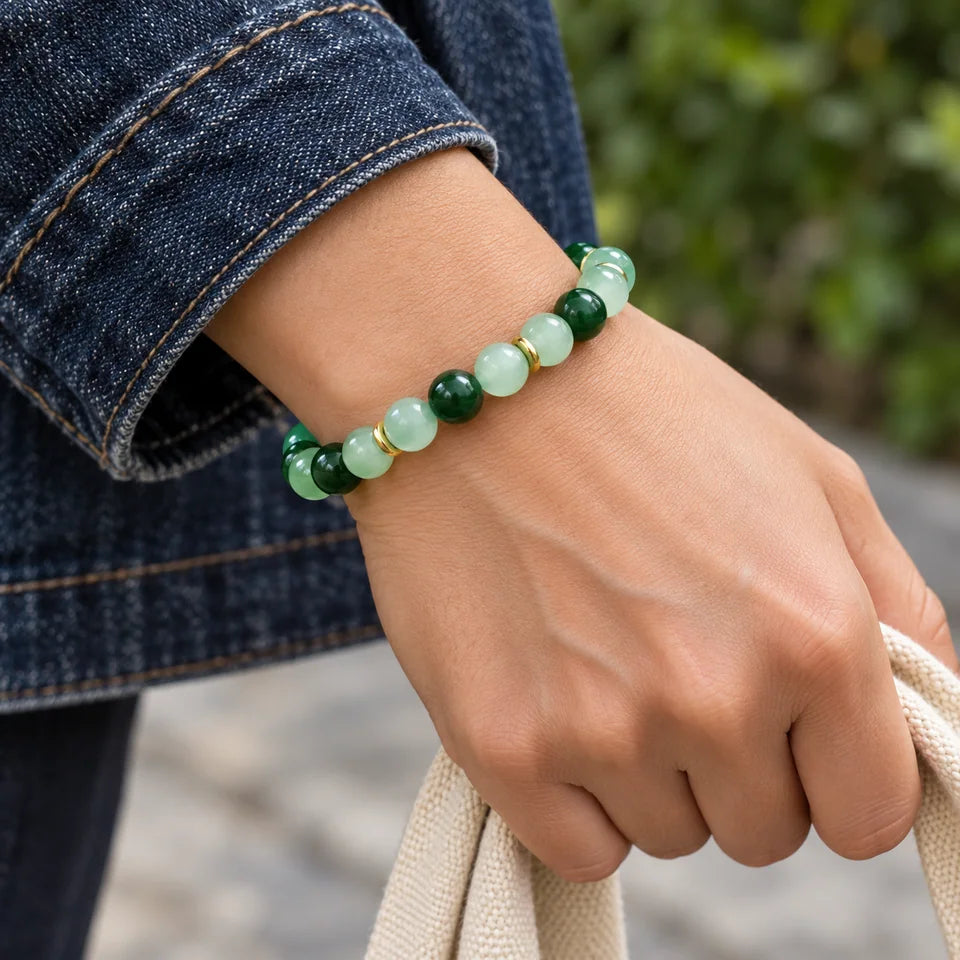 Green bracelet worn beside a dark denim cuff and a canvas bag handle.