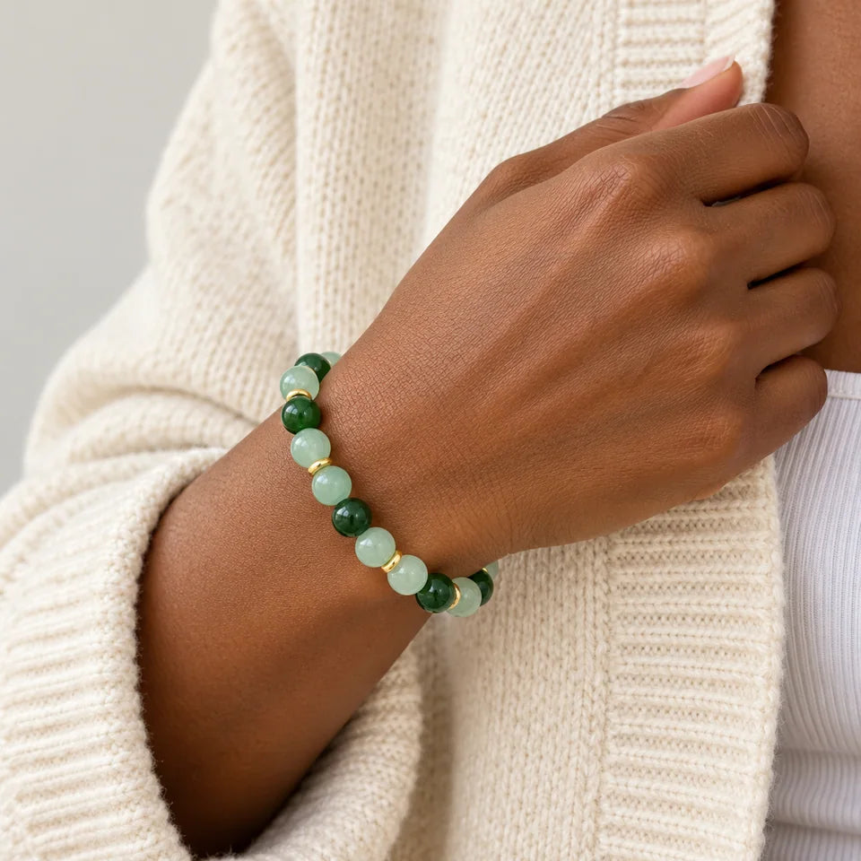 One green bracelet on a dark-skin adult wrist beside a cream cardigan.