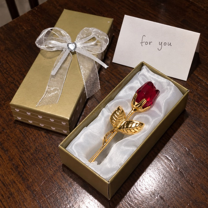 Ruby and gold rose gift on a walnut table.