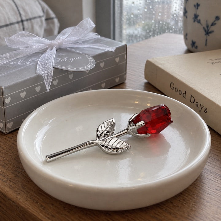 Ruby and silver rose lying on a white dish.